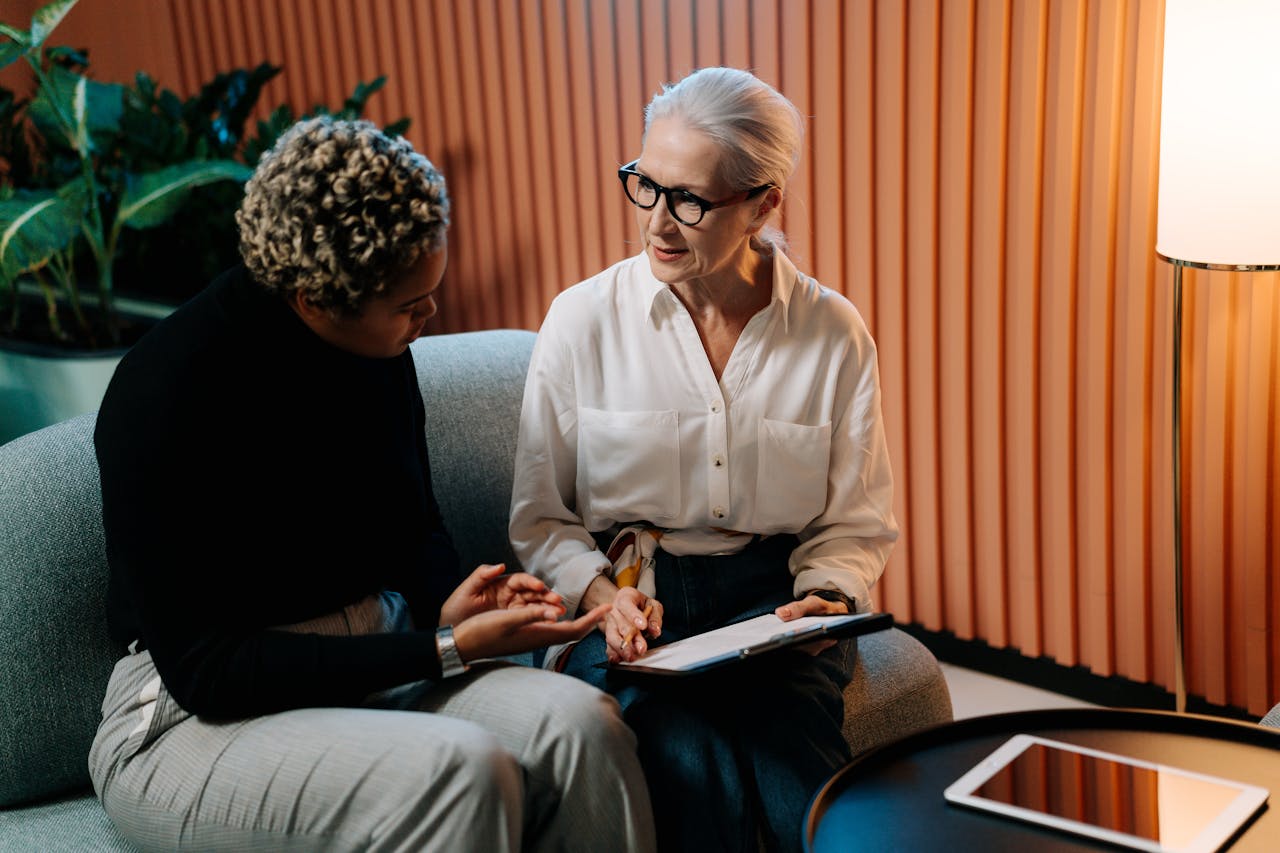 Two professional women engaged in a business discussion indoors with documents.